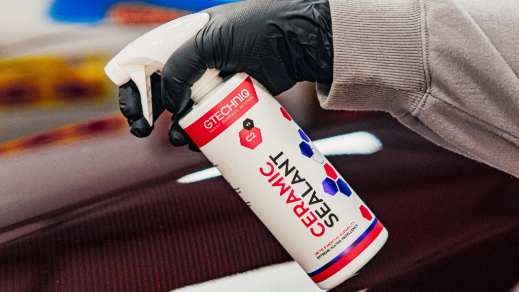 Individual spraying Gtechniq ceramic sealant solution on a car.