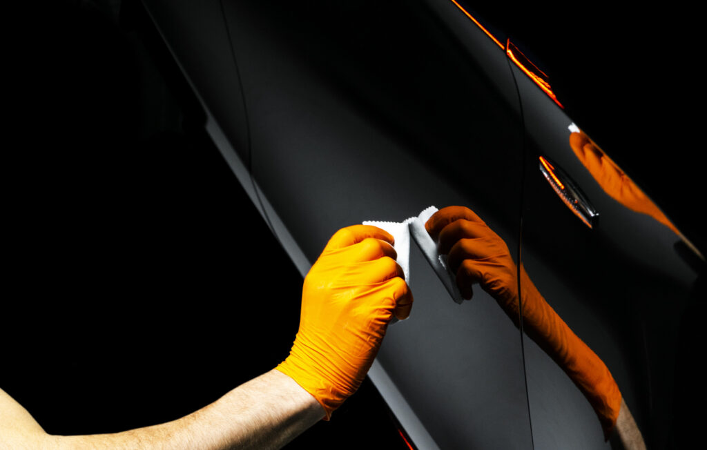 Car polish wax worker hands polishing car. Buffing and polishing vehicle with ceramic. Car detailing. Man holds a polisher in the hand and polishes the car with nano ceramic. Tools for polishing