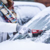 Woman cleaning snow from windshield, Scraping frozen ice glass. Winter car clean front windows.