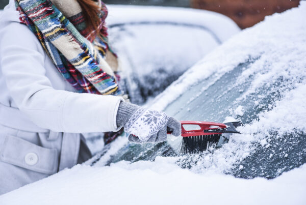 Woman cleaning snow from windshield, Scraping frozen ice glass. Winter car clean front windows.