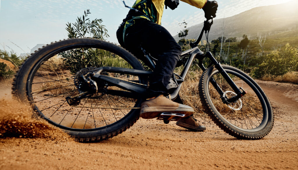 Sports, action and biker dirt racing on mountain bike enjoying riding, cycling and moving with speed. Extreme sports, mountain biking and athlete drifting on dirt road for fitness, adrenaline and fun
